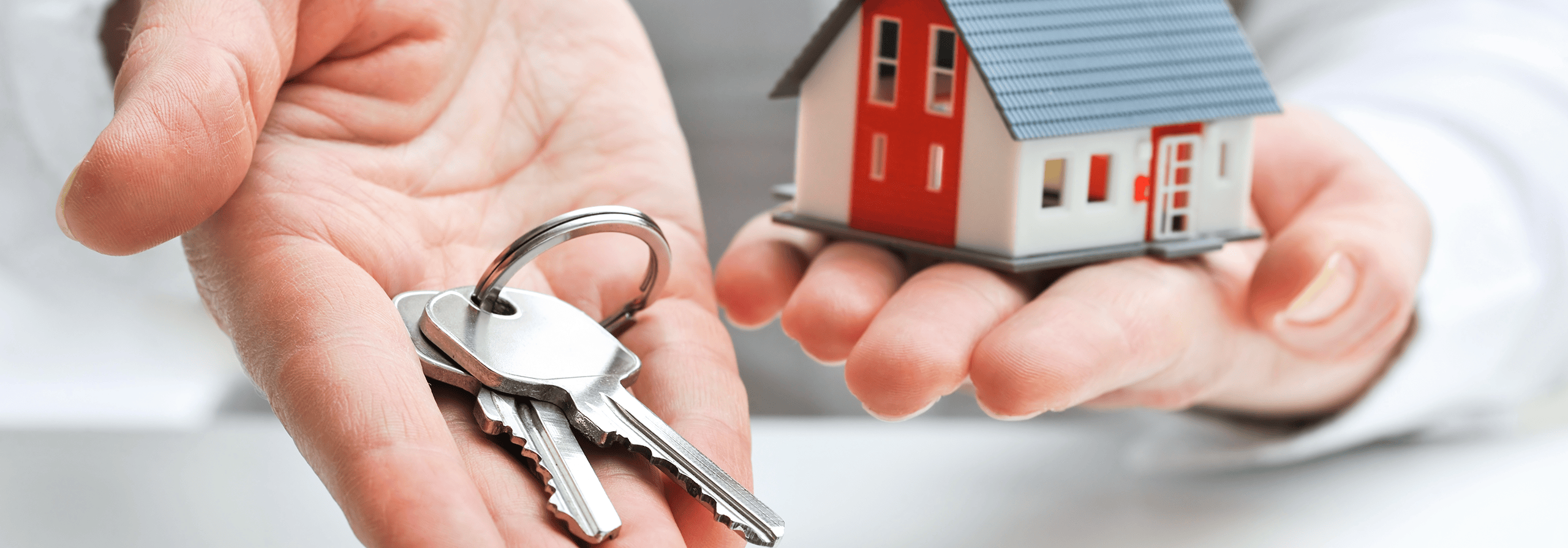 hands holding keys and a model home
